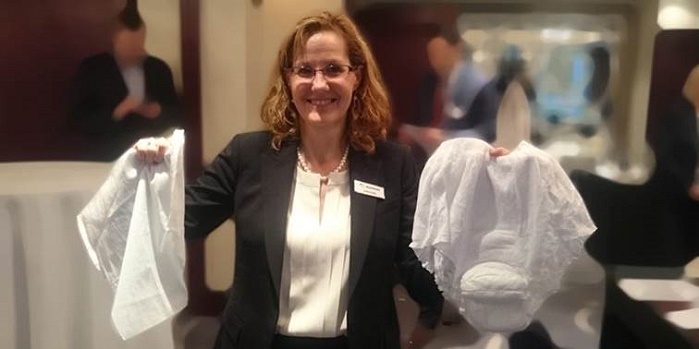 Lynda A. Kelly, Senior Vice President, Care business area at Suominen, showcasing modern pull-up pants and a conventional adult diaper. © Suominen