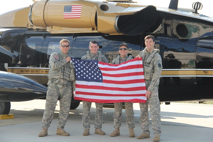 Sam Russo, founder of RePatriot Flag (far right), holding a RePatriot flag made from 10 recycled plastic bottles. © Unifi