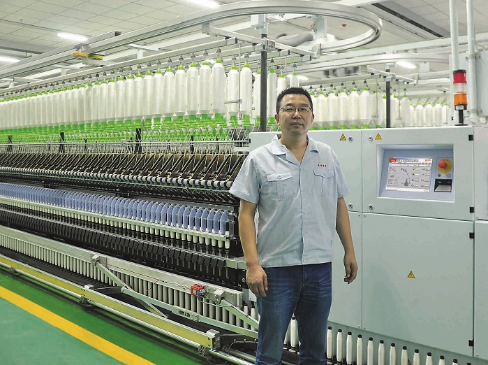Yang Renhong, Head of Spinning Department at Xianyang Textiles, in front of the ZinserRing 71. © Saurer Group