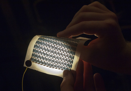 Graduate student Miles Barr hold a flexible and foldable array of solar cells that have been printed on a sheet of paper. Photo: Patrick Gillooly