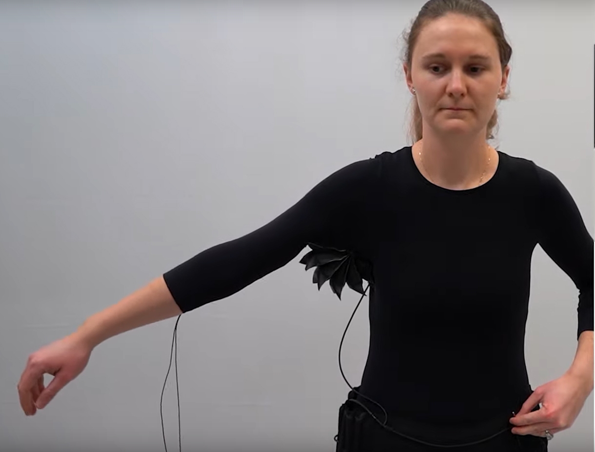 Powered by walking, a shirt with a bellows-like actuator attached at the armpit expands to enable the wearer to pick up a ten-pound object. © Preston Innovation Lab