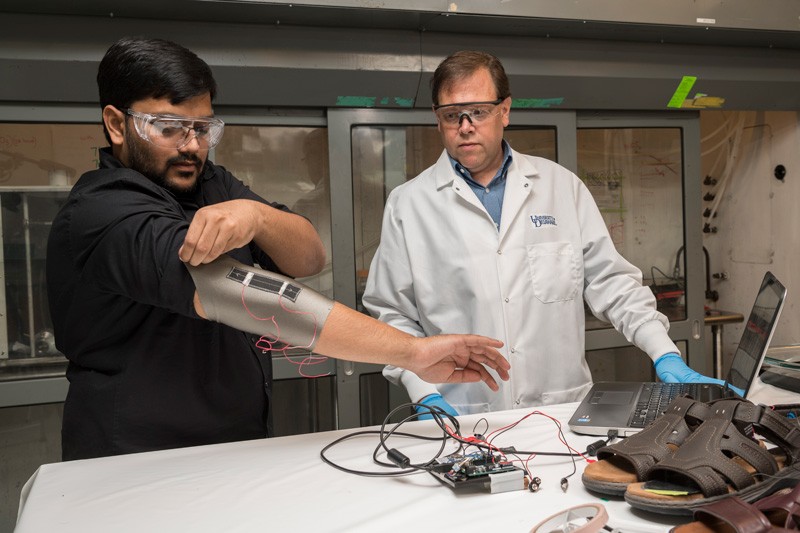 Sagar Doshi (left) and Erik Thostenson test an elbow sleeve outfitted with one of their novel sensors.